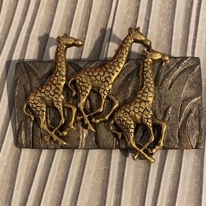 Darlene metal brooch featuring three running giraffes in gold and silver tones.